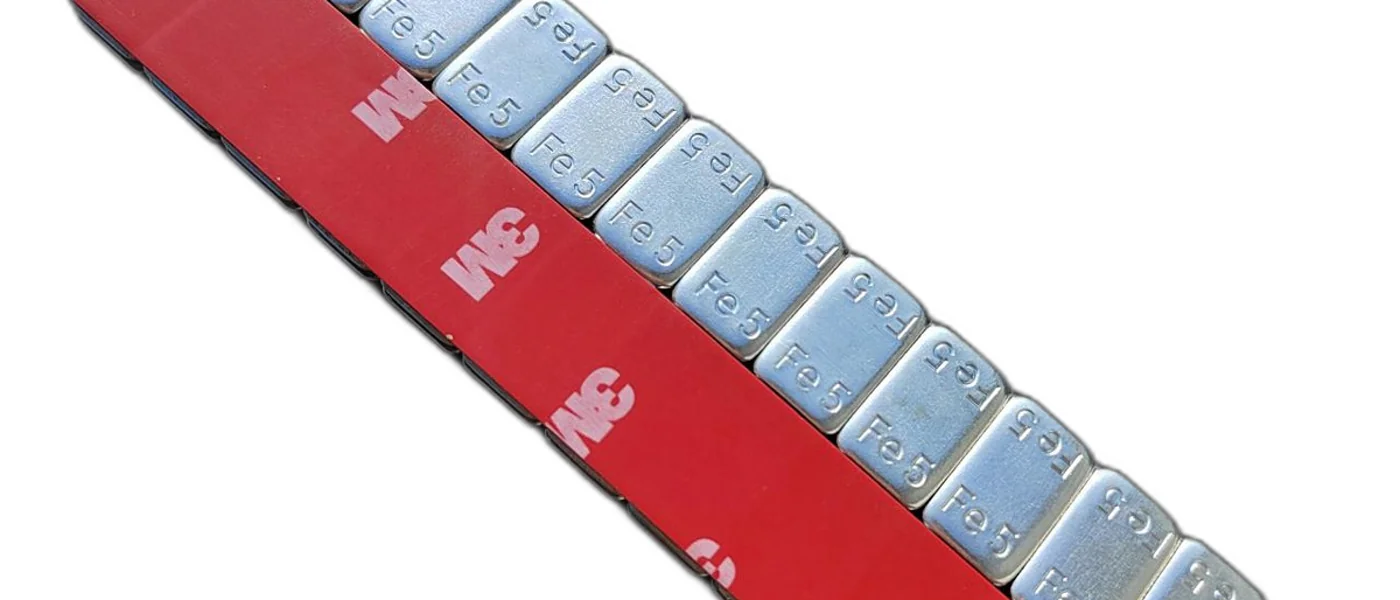 Close up of Fe adhesive wheel weight strip with red 3M tape liner